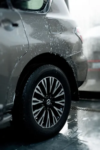 A freshly rinsed alloy wheel and wet silver car body.