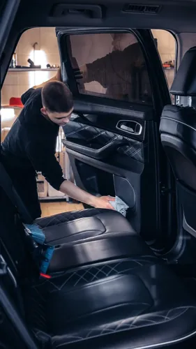 A detailer wiping leather seats inside a large vehicle.
