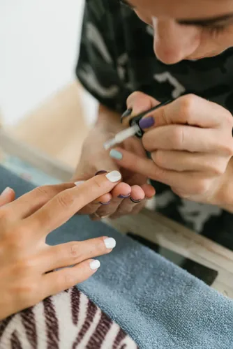 A nail technician painting a client’s fingernails.