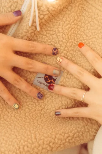 Hands displaying different colourful painted nail designs.