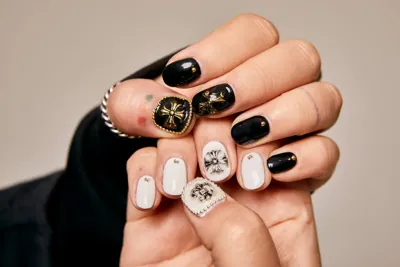 Black and white nails with detailed gold and illustrated accents.