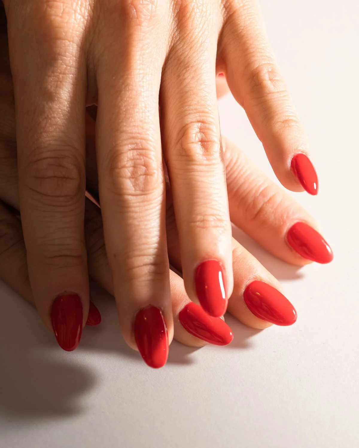 A glossy red manicure, shown as an example of nail work.