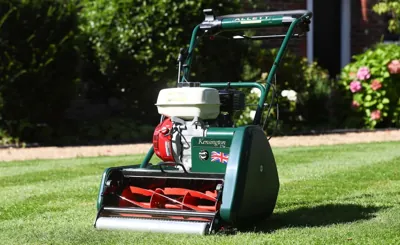 A cylinder mower resting on a freshly striped green lawn.